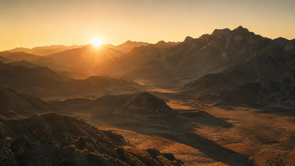 Golden sunrise over a rugged desert mountain range, symbolizing leadership transition and authority in Deuteronomy.