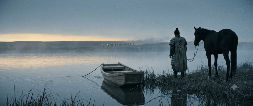 A cinematic wide-angle shot of historical Chinese warrior Xiang Yu standing alone on the bank of the misty Wu River at dawn, looking away from a small empty wooden ferry boat and towards distant pursuers, with his dark horse beside him.